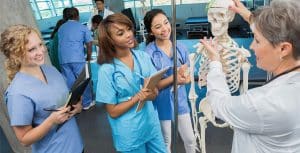 A woman doctor showing 3 women a human skeleton